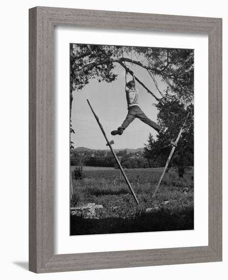 Kenneth Merriman Swinging on Tree Limb after Kicking Away Stilts-null-Framed Photographic Print
