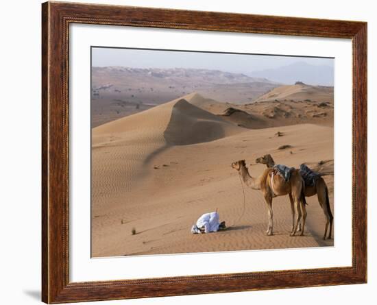 Kneeling to Pray in Desert, Holding Camels by Halters to Prevent Them Wandering Off Amongst Dunes-John Warburton-lee-Framed Photographic Print