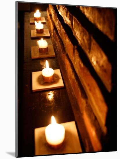 Lighted Candles and Brick Wall-Michele Molinari-Mounted Photographic Print