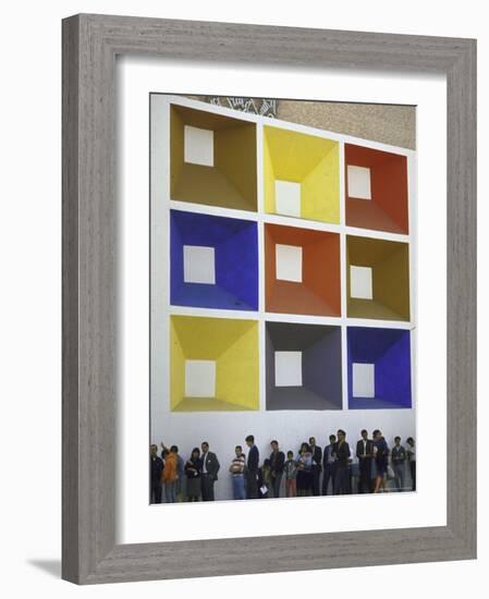 Line of People under Building Facade Painted with Brightly Colored Geometric Pattern-John Dominis-Framed Photographic Print