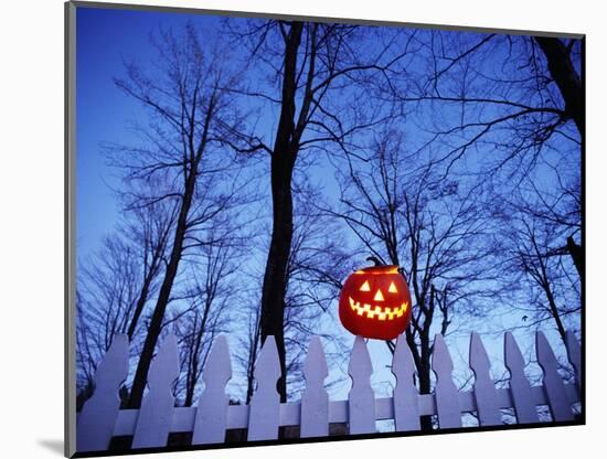 Lit Jack o'-Lantern Perched on Picket Fence-Ralph Morsch-Mounted Photographic Print