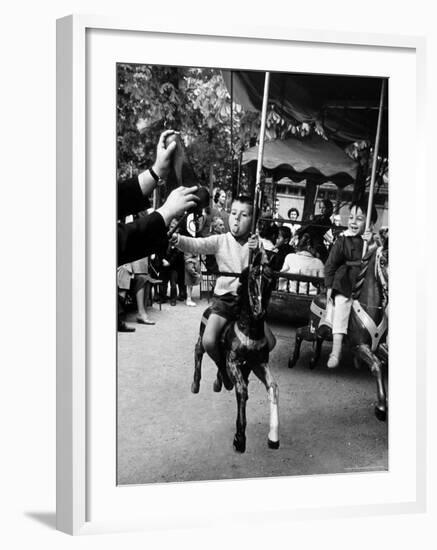 Little Boy on Merry Go Round at the Tuileries Gardens, Sticking Out His Tongue-Alfred Eisenstaedt-Framed Photographic Print