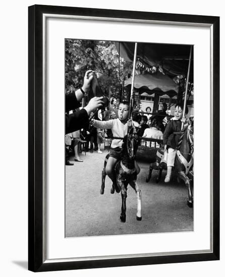 Little Boy on Merry Go Round at the Tuileries Gardens, Sticking Out His Tongue-Alfred Eisenstaedt-Framed Photographic Print