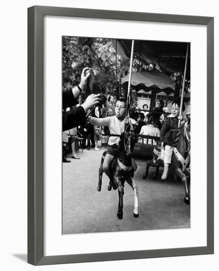 Little Boy on Merry Go Round at the Tuileries Gardens, Sticking Out His Tongue-Alfred Eisenstaedt-Framed Photographic Print