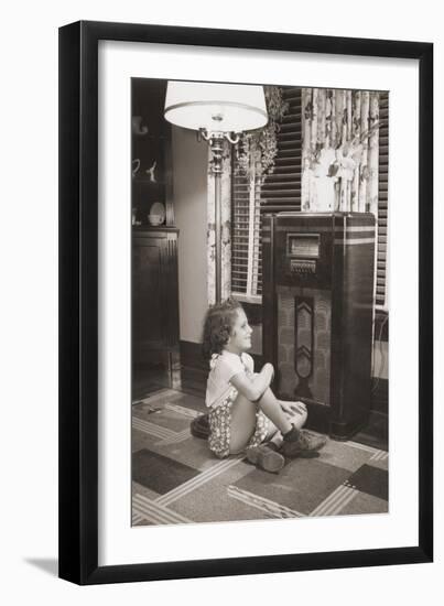 Little Girl Smiles as She Enjoys a Radio Program in the 1930s-null-Framed Photo