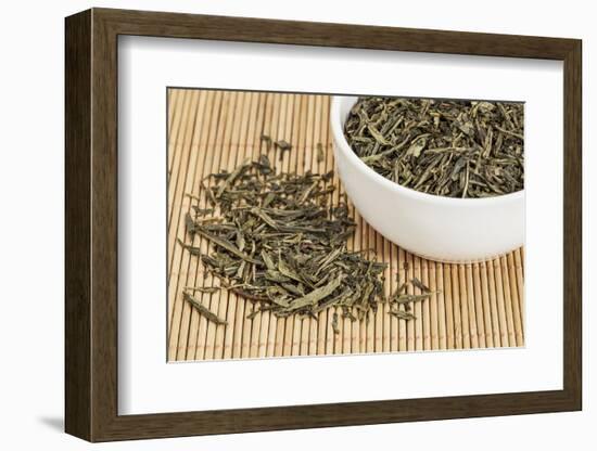 Loose Leaf Sencha Green Tea in a White China Cup and Spilled over Bamboo Mat-PixelsAway-Framed Photographic Print