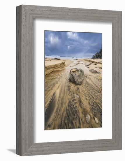 Low angle of a stream flowing around a rock heading into the ocean with stormy skies and a rainbow-Sheila Haddad-Framed Photographic Print