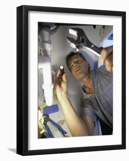 Low Angle View of a Young Man Checking the Plumbing with a Flashlight-null-Framed Photographic Print