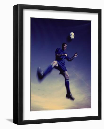 Low Section View of a Soccer Player Jumping in Mid Air to Head a Soccer Ball-null-Framed Photographic Print