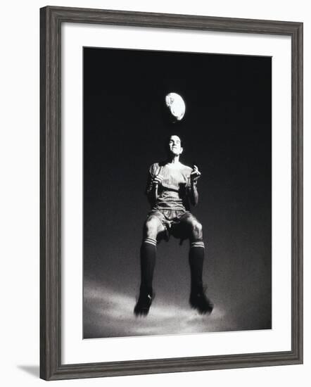 Low Section View of a Soccer Player Jumping in Mid Air to Head a Soccer Ball-null-Framed Photographic Print