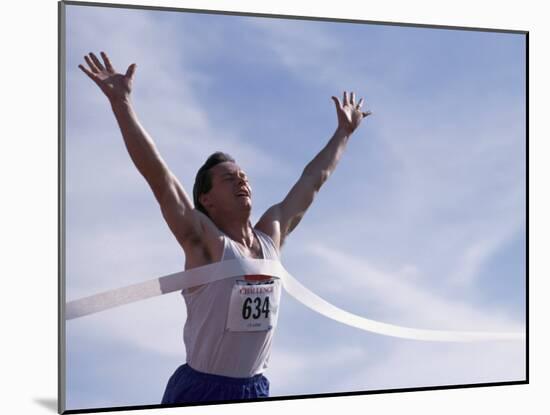 Male Runner Victorious at the Finish Line in a Track Race-null-Mounted Photographic Print