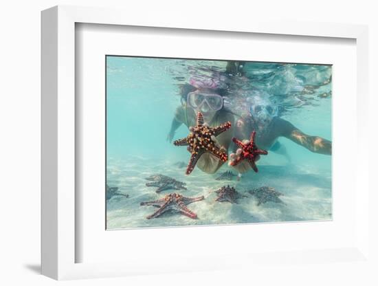 Man and woman with scuba masks showing starfish swimming underwater in the exotic lagoon-Roberto Moiola-Framed Photographic Print