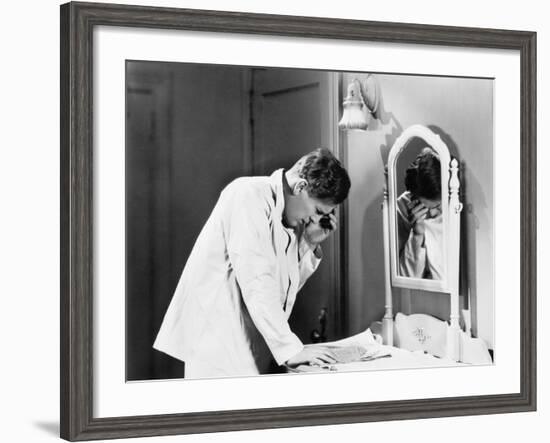 Man Bending over a Piece of Paper on His Dresser and Holding His Head-null-Framed Photo