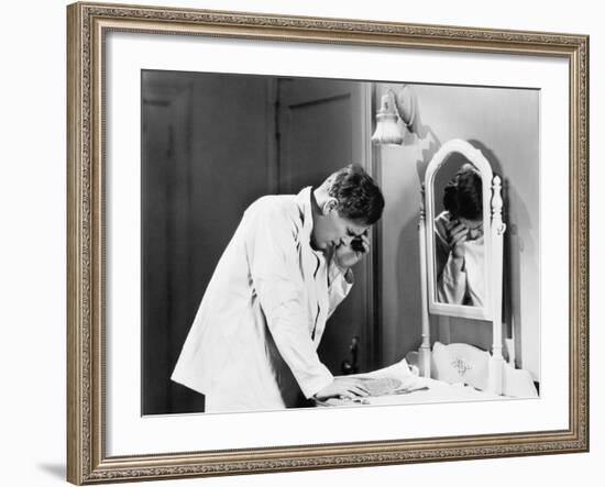 Man Bending over a Piece of Paper on His Dresser and Holding His Head-null-Framed Photo