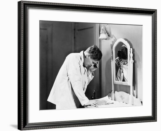 Man Bending over a Piece of Paper on His Dresser and Holding His Head-null-Framed Photo