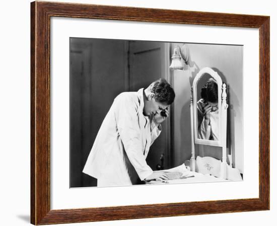 Man Bending over a Piece of Paper on His Dresser and Holding His Head-null-Framed Photo