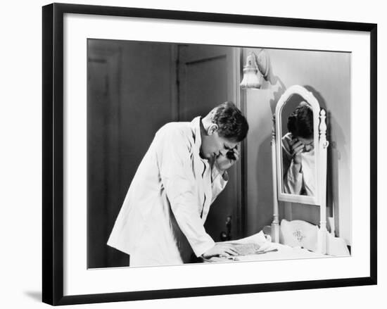 Man Bending over a Piece of Paper on His Dresser and Holding His Head-null-Framed Photo