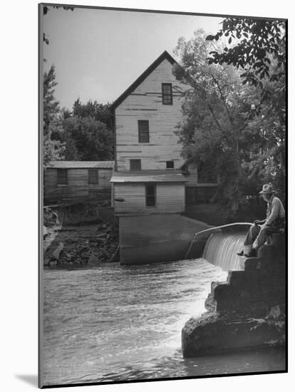 Man Fishing Beside a Waterfall and a 100 Year Old Mill-Bob Landry-Mounted Photographic Print