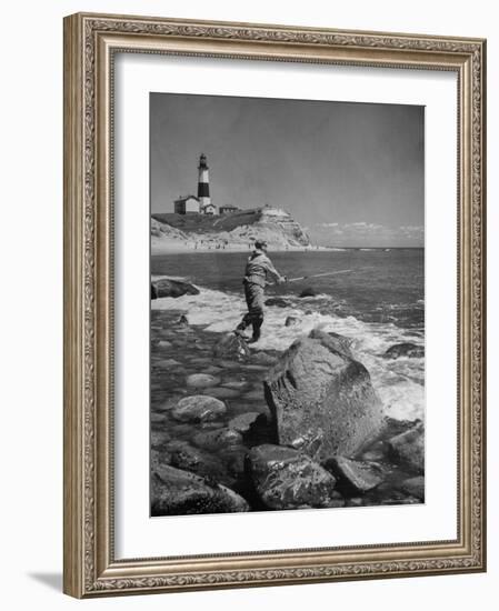 Man Fishing Off Montauk Point. Montauk Lighthouse Visible in Background-Alfred Eisenstaedt-Framed Photographic Print