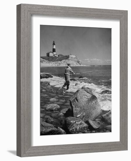 Man Fishing Off Montauk Point. Montauk Lighthouse Visible in Background-Alfred Eisenstaedt-Framed Photographic Print