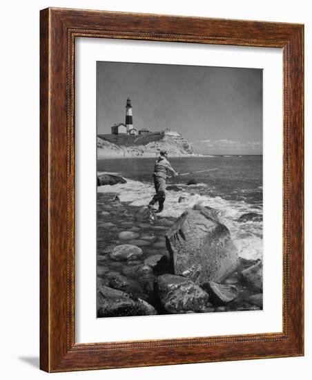 Man Fishing Off Montauk Point. Montauk Lighthouse Visible in Background-Alfred Eisenstaedt-Framed Photographic Print