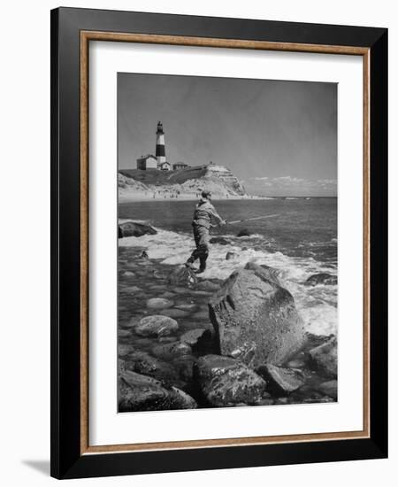 Man Fishing Off Montauk Point. Montauk Lighthouse Visible in Background-Alfred Eisenstaedt-Framed Photographic Print