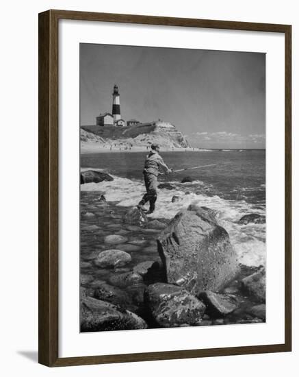 Man Fishing Off Montauk Point. Montauk Lighthouse Visible in Background-Alfred Eisenstaedt-Framed Photographic Print