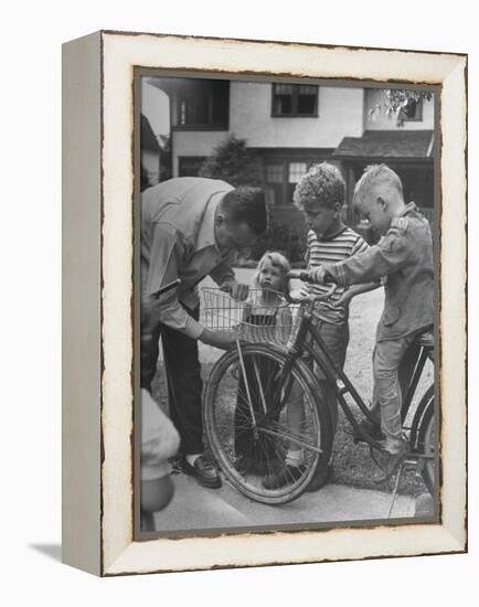 Man Fixing Basket on Bicycle as Children Watch Attentively-Nina Leen-Framed Premier Image Canvas