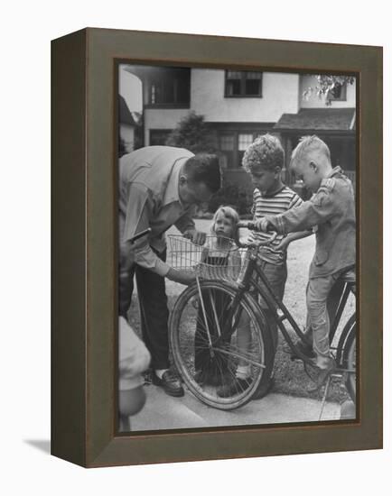 Man Fixing Basket on Bicycle as Children Watch Attentively-Nina Leen-Framed Premier Image Canvas