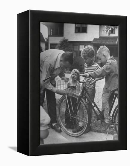 Man Fixing Basket on Bicycle as Children Watch Attentively-Nina Leen-Framed Premier Image Canvas