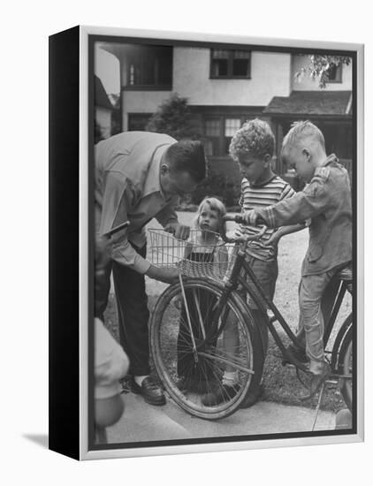 Man Fixing Basket on Bicycle as Children Watch Attentively-Nina Leen-Framed Premier Image Canvas