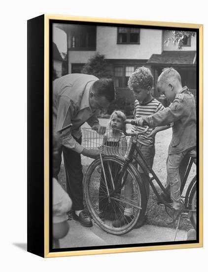 Man Fixing Basket on Bicycle as Children Watch Attentively-Nina Leen-Framed Premier Image Canvas