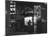 Man in a Raincoat Studies the Westminster City Guide Map at Night in Piccadilly Circus-null-Mounted Photographic Print