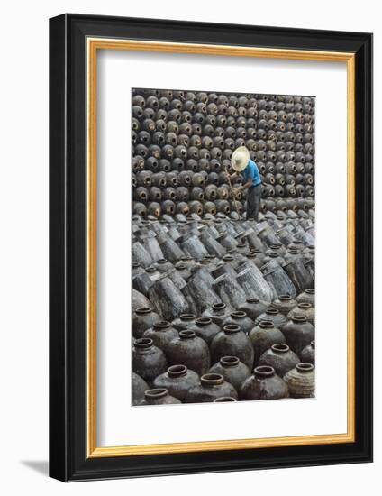 Man in the middle of big pile of wine jars stacked up at a local rice winery, Wuxi, China-Keren Su-Framed Photographic Print