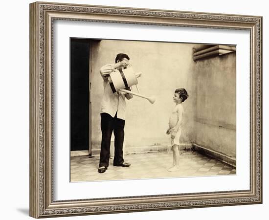 Man Is Sprinkling Boy with Water from Watering Can, 20th Century-Andrew Pitcairn-knowles-Framed Giclee Print