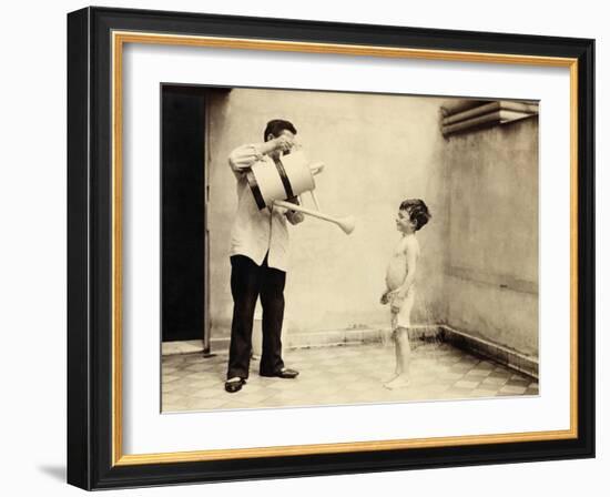 Man Is Sprinkling Boy with Water from Watering Can, 20th Century-Andrew Pitcairn-knowles-Framed Giclee Print