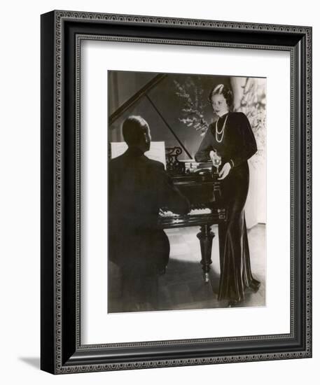 Man Plays a Piano and Looks up at a Glamorous Woman in a Long Dress--Framed Photographic Print