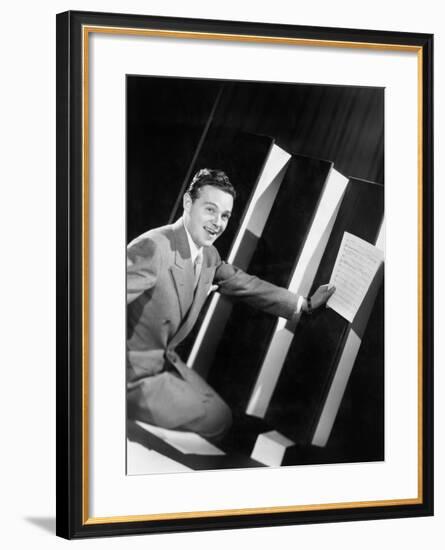 Man Sitting with Oversized Books Holding Sheet Music in His Hands-null-Framed Photo