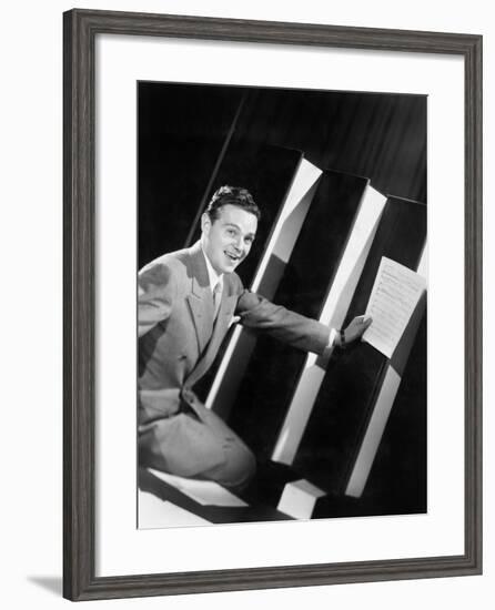Man Sitting with Oversized Books Holding Sheet Music in His Hands-null-Framed Photo