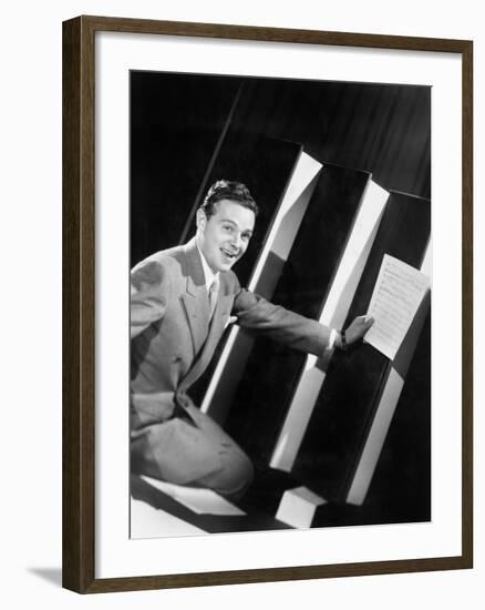 Man Sitting with Oversized Books Holding Sheet Music in His Hands-null-Framed Photo