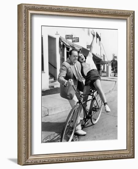 Man Trying to Balance an Exuberant Woman on a Bicycle-null-Framed Photo