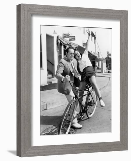 Man Trying to Balance an Exuberant Woman on a Bicycle-null-Framed Photo