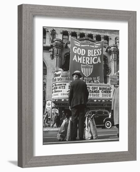 Man with Shopping Bags in Front of Million Dollar Theatre Emblazoned with God Bless America Banner-Bob Landry-Framed Photographic Print