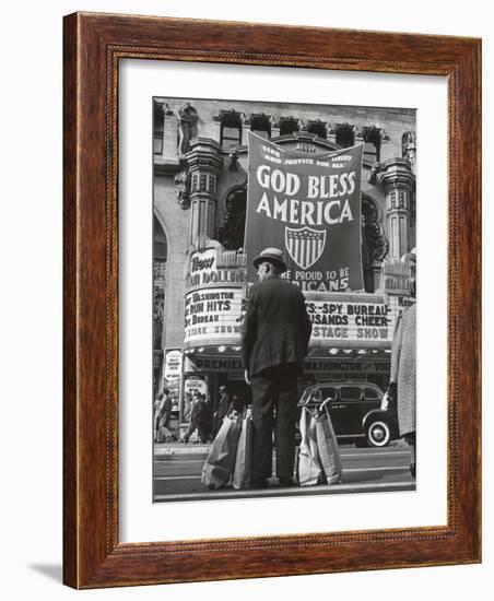 Man with Shopping Bags in Front of Million Dollar Theatre Emblazoned with God Bless America Banner-Bob Landry-Framed Photographic Print