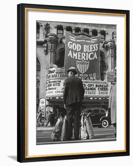 Man with Shopping Bags in Front of Million Dollar Theatre Emblazoned with God Bless America Banner-Bob Landry-Framed Photographic Print