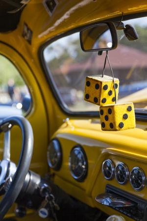 Fuzzy dice hang from the rear-view mirror of a vintage 'low rider