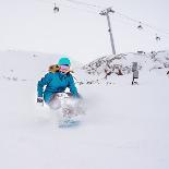 Young Woman Snowboarder in Motion on Snowboard in Mountains-Maxim Blinkov-Photographic Print