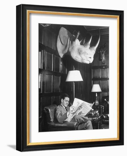 Member Reading Newspaper in Smoking Room at the Harvard Club Beneath a Rhino Head Trophy-Alfred Eisenstaedt-Framed Photographic Print