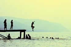 Silhouettes of Kids Who Jump off Dock on the Lake at Sunset.-Mita Stock Images-Photographic Print