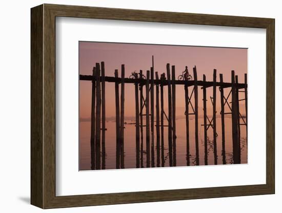 Monk walking at sunrise over the lake near wooden footbridge. Taungthaman Lake, Myanmar.-Michele Niles-Framed Photographic Print